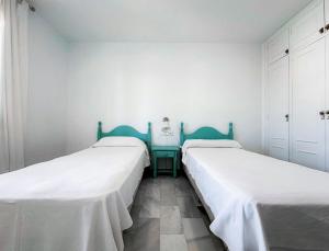two beds in a room with white walls at Vistahermosa Gestur Apartamentos in El Puerto de Santa María