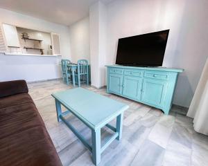 a living room with a blue cabinet with a tv at Vistahermosa Gestur Apartamentos in El Puerto de Santa María