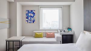 a room with two beds and a couch and a window at Holiday Inn Express Sapporo Susukino by IHG in Sapporo +93 photos