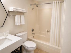 a white bathroom with a toilet and a tub and a sink at Dickinson Inn in Dickinson