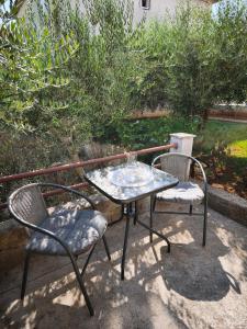 a glass table and two chairs on a patio at Apartman Ivona in Zadar
