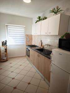 a kitchen with white cabinets and a stove top oven at Apartman Ivona in Zadar +8 photos