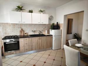 a kitchen with white cabinets and a white refrigerator at Apartman Ivona in Zadar