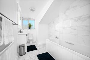 a white bathroom with a tub and a toilet at Providence Suites 1 Bedroom Sleeps 4 Perfect for Contractors and Families and Solo Travellers in Fallings Park +40 photos