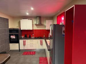 a kitchen with red walls and white cabinets and a refrigerator at La Villa La ri Deye in Kourou