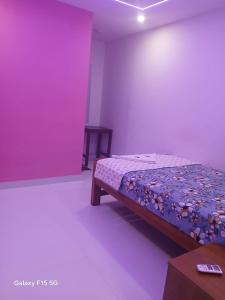 a bedroom with a bed and a purple wall at Dolphin beach in Varkala