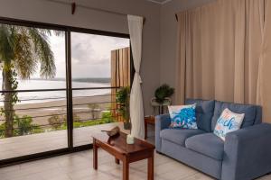 a living room with a blue couch and a large window at Mar y Sombra Villas in Quepos