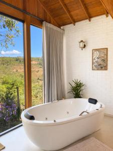 a bath tub in a bathroom with a large window at Chalés Colina dos Colibris in Santa Teresa