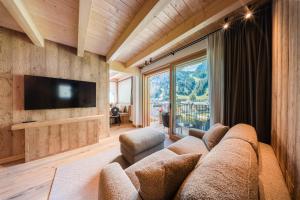 a living room with a couch and a large window at AlpeLuce Mountain Chalet in Arabba