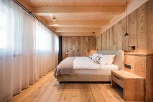 a bedroom with a bed and a wooden wall at AlpeLuce Mountain Chalet in Arabba