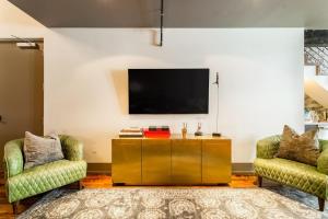 a living room with two green chairs and a tv at Tasteful Loft in Nashville