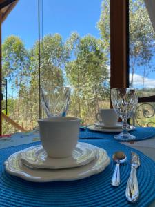 a table with plates and glasses on a blue table cloth at Chalés Colina dos Colibris in Santa Teresa +42 photos