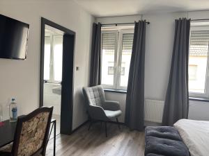 a bedroom with a bed and a chair and a window at Hotel Zur Krone in Nordwalde