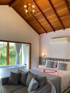 a bedroom with a large bed and a couch at Chalés Colina dos Colibris in Santa Teresa