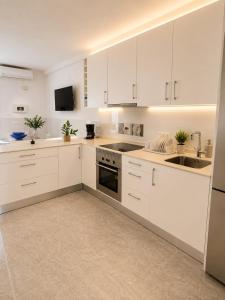 a white kitchen with white cabinets and a sink at Little Los Emilios in Torrevieja