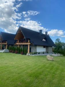 a house with a black roof and a yard at Zbójeckie Sioło in Bukowina Tatrzańska