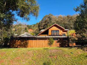a house with a wooden fence and trees at Cabanha Tessaro in Chapecó