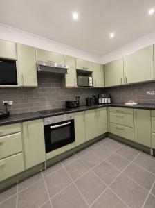 a large kitchen with green cabinets and appliances at The Promenade House in New Brighton