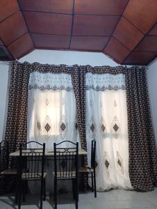 a dining room with a table and chairs and curtains at Cosy appartement à Nongo in Conakry