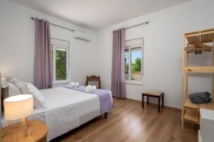 a bedroom with a bed and two windows at Polytimi Summerhouse in Ialysos