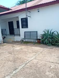 a bench sitting in front of a white house at Cosy appartement à Nongo in Conakry