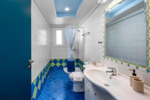 a blue and white bathroom with a toilet and a sink at Polytimi Summerhouse in Ialysos +27 photos