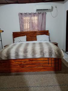 a bed with a wooden headboard and a window at Cosy appartement à Nongo in Conakry