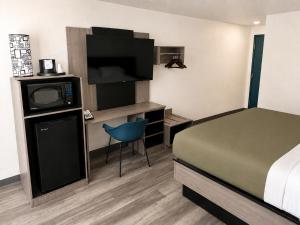 a hotel room with a bed and a tv and a desk at Dickinson Inn in Dickinson