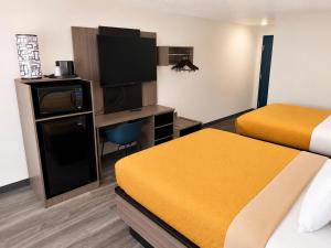 a hotel room with two beds and a desk at Dickinson Inn in Dickinson