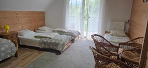 a bedroom with two beds and chairs and a window at Przystanek Bieszczad in Lutowiska