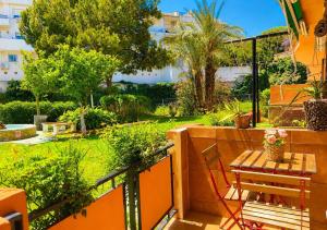 a balcony with a table and a chair and a garden at Estudio con piscina y jardines a 2 min de la playa - Fuengirola in Fuengirola +1 photo