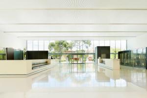 a large white lobby with large windows and white floors at Le Meridien Ra Beach Hotel and Spa in El Vendrell