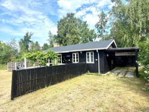 a black house with a fence in a yard at M27-Vaeggerlose-Tornbladvej-14 in Bøtø By