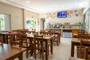 a restaurant with wooden tables and chairs and a kitchen at Pousada Cataratas in Foz do Iguaçu