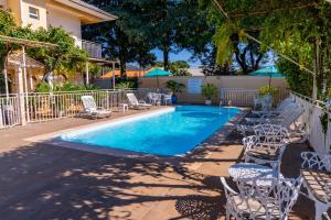a swimming pool with white chairs and tables at Pousada Cataratas in Foz do Iguaçu