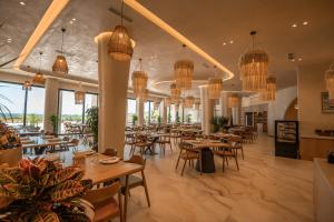 ein Restaurant mit Tischen, Stühlen und Kronleuchtern in der Unterkunft Avaris Hotel in Dhërmi
