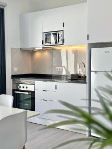 a kitchen with white cabinets and a microwave at Waves Madeira II in Caniçal +5 photos