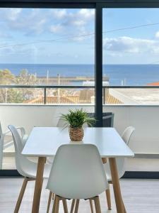 a white table and chairs with a view of the ocean at Waves Madeira II in Caniçal