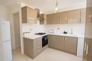 a kitchen with brown cabinets and a stove top oven at Hill's View - 6 Sleeps - 10 minute walk to the town in Barnstaple