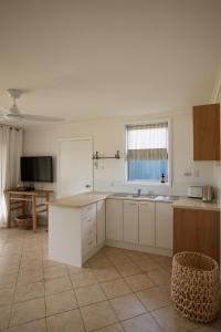 a large kitchen with white cabinets and a table at The Mullet in Nambucca Heads