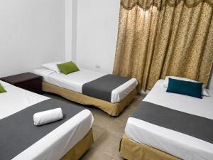 a room with three beds and curtains at Hotel Charmin in Gaira