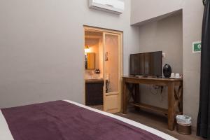 a bedroom with a bed and a desk with a television at Casa Brunella - Hotel Boutique Querétaro in Querétaro