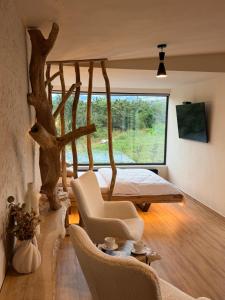 a bedroom with a bed and chairs and a large window at KUBIQ 2 Transalpina in Sebeş
