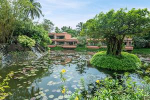 a pond in front of houses with a tree and flowers at The St. Regis Goa Resort in Cavelossim