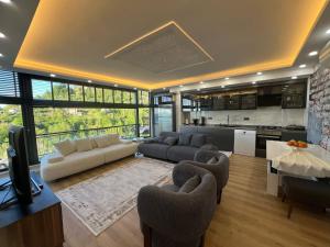 a living room with a couch and chairs and a kitchen at cam teraslı köyevi in Cayeli