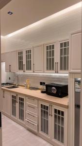 a large kitchen with white cabinets and a sink at شاليه وقاعة ايليت in Buraydah