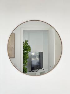 a mirror on a white wall with a television at Waves Madeira I in Caniçal
