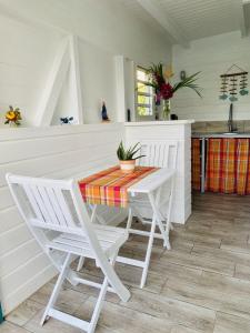 a white kitchen with a table and chairs at Papaye et coconut in Anse-Bertrand