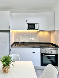 a white kitchen with a table and a microwave at Waves Madeira I in Caniçal