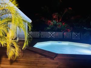 a swimming pool with a fence and a palm tree at Papaye et coconut in Anse-Bertrand
